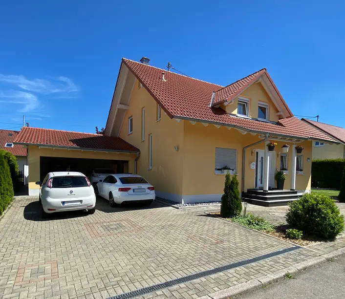 Einfamilienhaus mit rotem Ziegeldach, Carport und gepflastertem Vorplatz