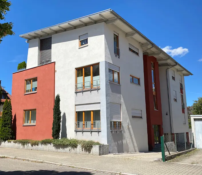 Modernes Wohnhaus mit weißer Fassade und rotem Fassadenelement