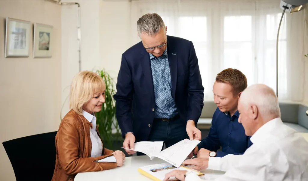Vier Personen besprechen Unterlagen an einem Besprechungstisch im Büro
